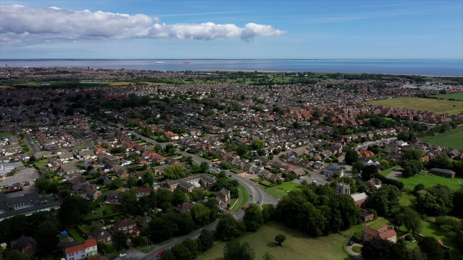 Aerial view of homes and green spaces in North East Lincolnshire with the Humber Estuary beyond